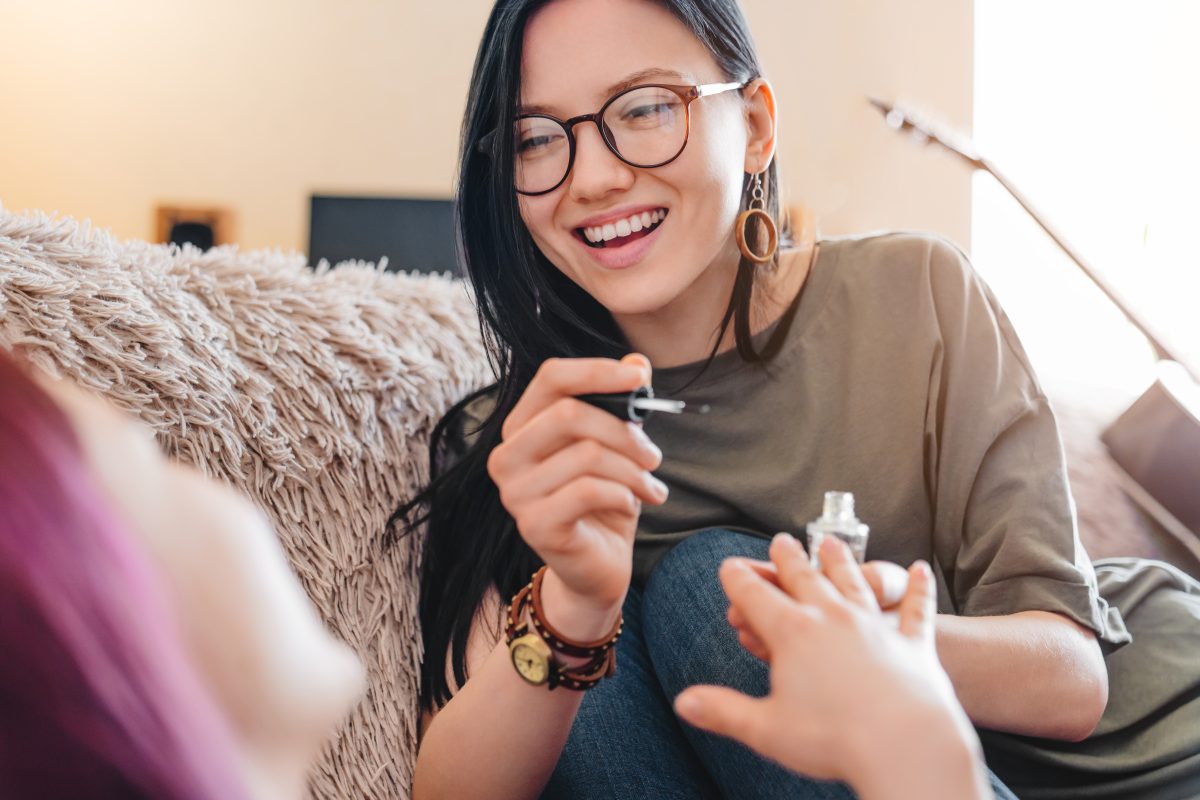 Close up of young female friends polishing nails indoors