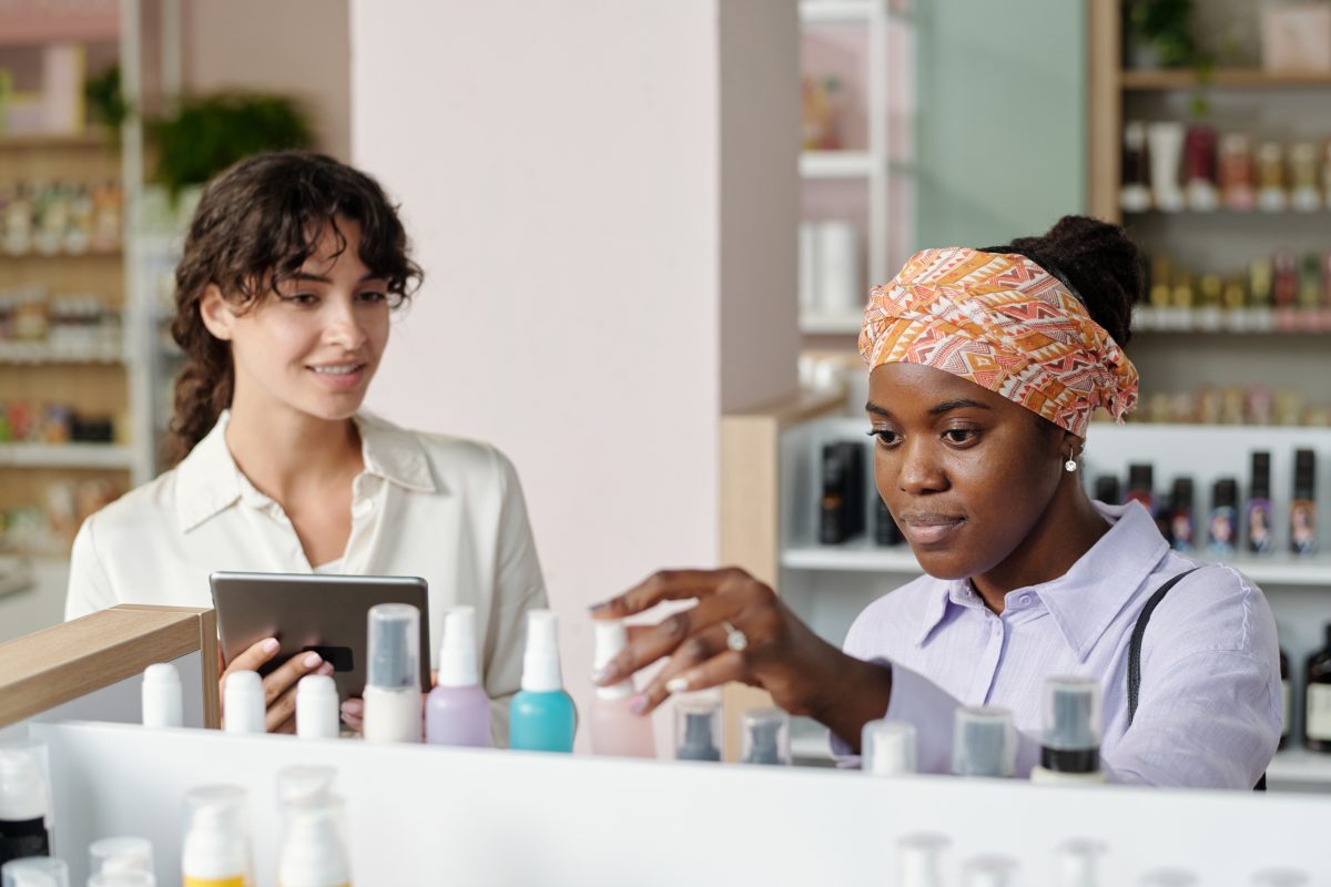 Young African American female consumer choosing beautycare product from huge assortment while standing in front of display. Nail supply stores in Canada. Nail salons in Canada.
