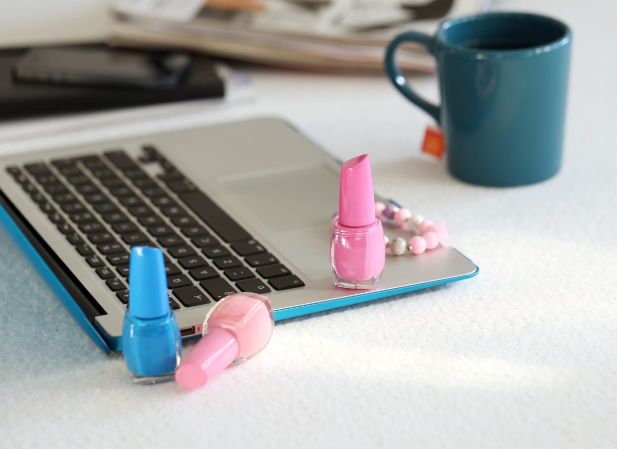 home-based nail business tools: Laptop, mug and nail polish on the table