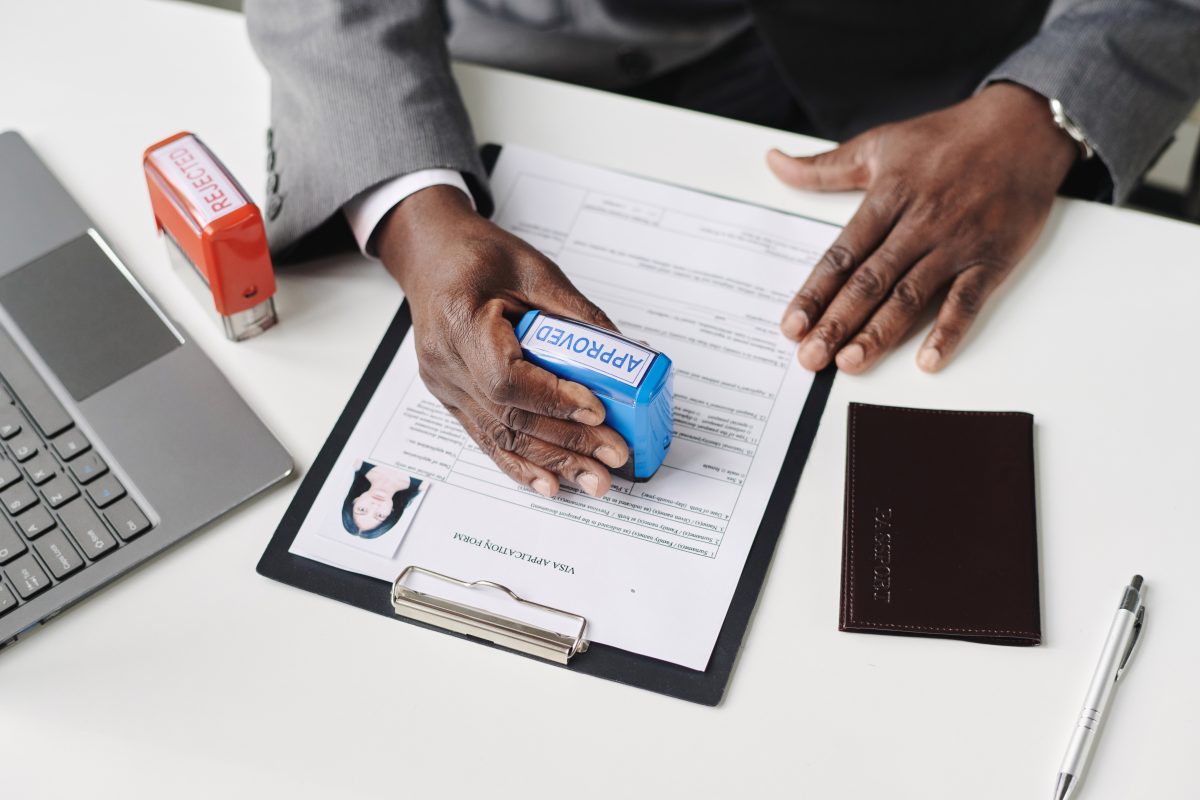 home-based nail business. High angle view of African American man approving visa in office