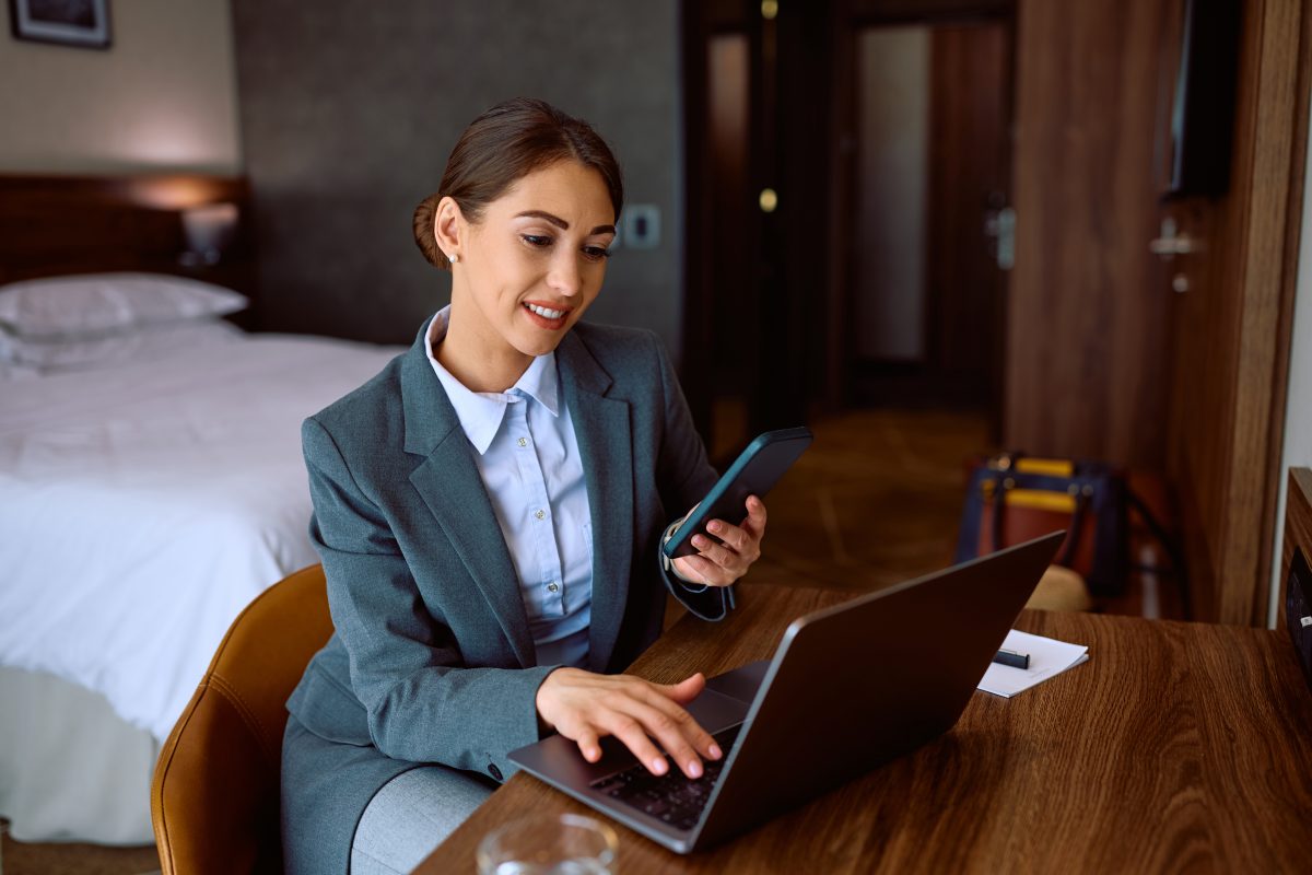 Young entrepreneur using laptop and mobile phone while staying at the hotel during her business travel. home-based nail business.