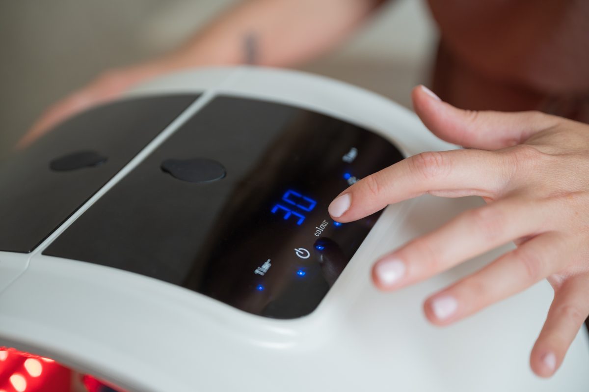 Beautician's hand adjusting hydrafacial machine for a skincare treatment in a beauty salon, enhancing client wellness and skin rejuvenation