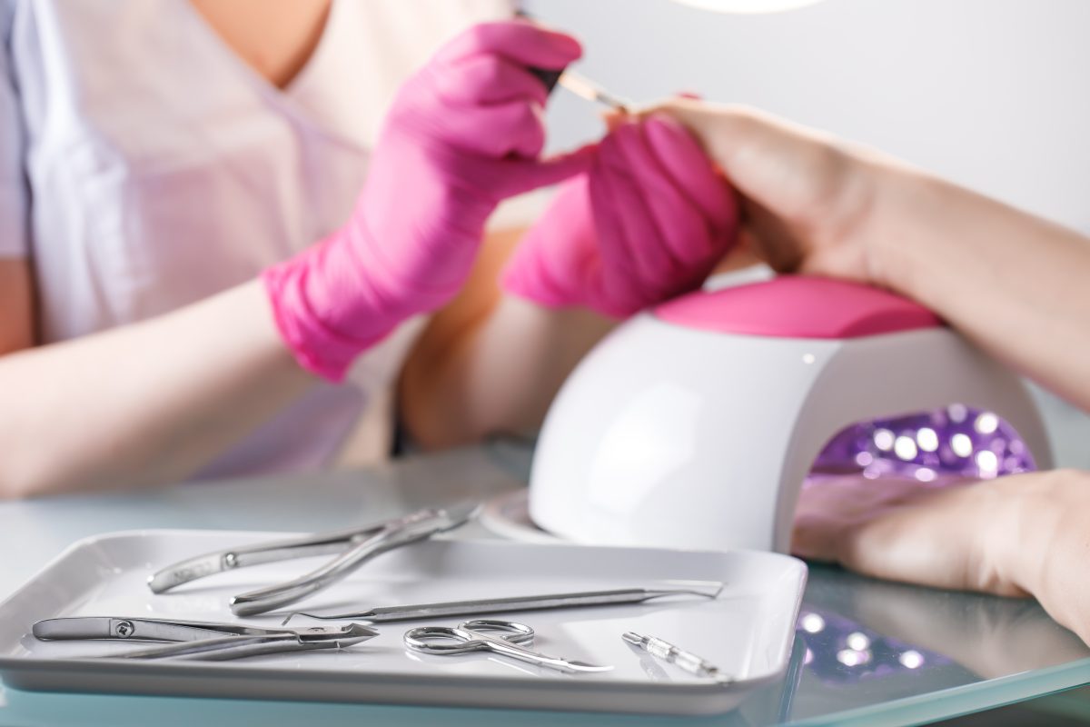 Curing Gel Polish. Professional tools for manicure. beautician applying Polish nails to woman nails on background.