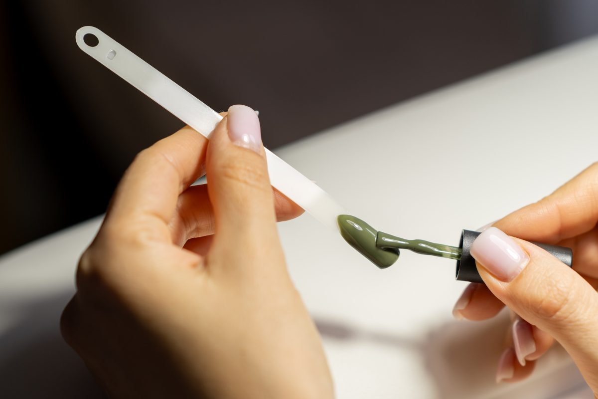A manicurist applies gel nail polish to empty tips as a sample for future clients. Large range of gel polishes. Spa body care concept. Nail technician
