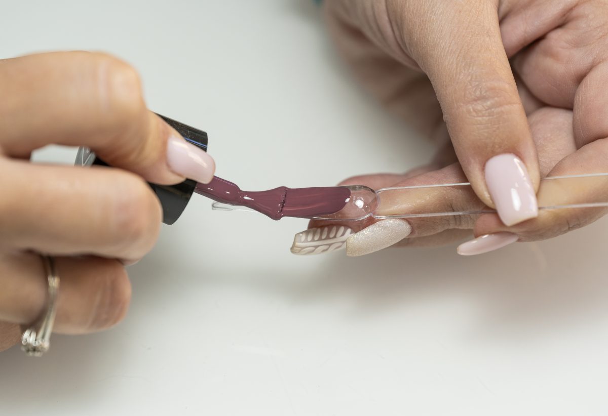 Close-up of a female manicurist showing a nail paint color to a client with a nail swatch