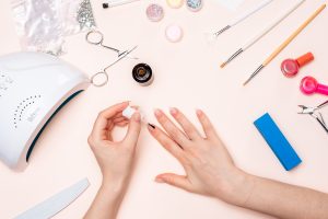 Hands girl applying gel to her nails with a brush. the view from the top. Gel vs. Dip Powder