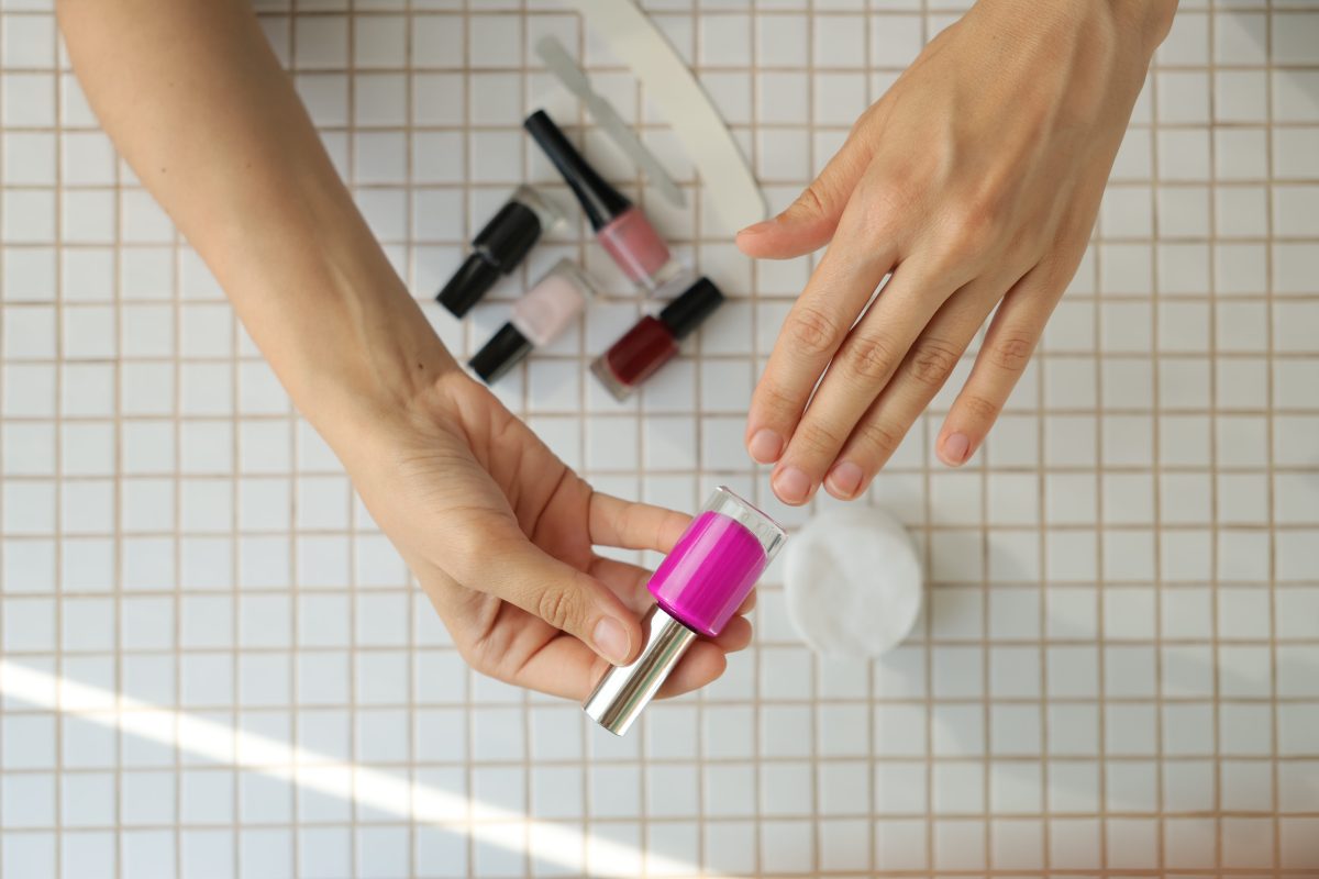 lady chooses color of nail polish. woman's hand and nail polish on table background. manicure and pedicure at home beauty salon. cuticle removal and hand skin care.