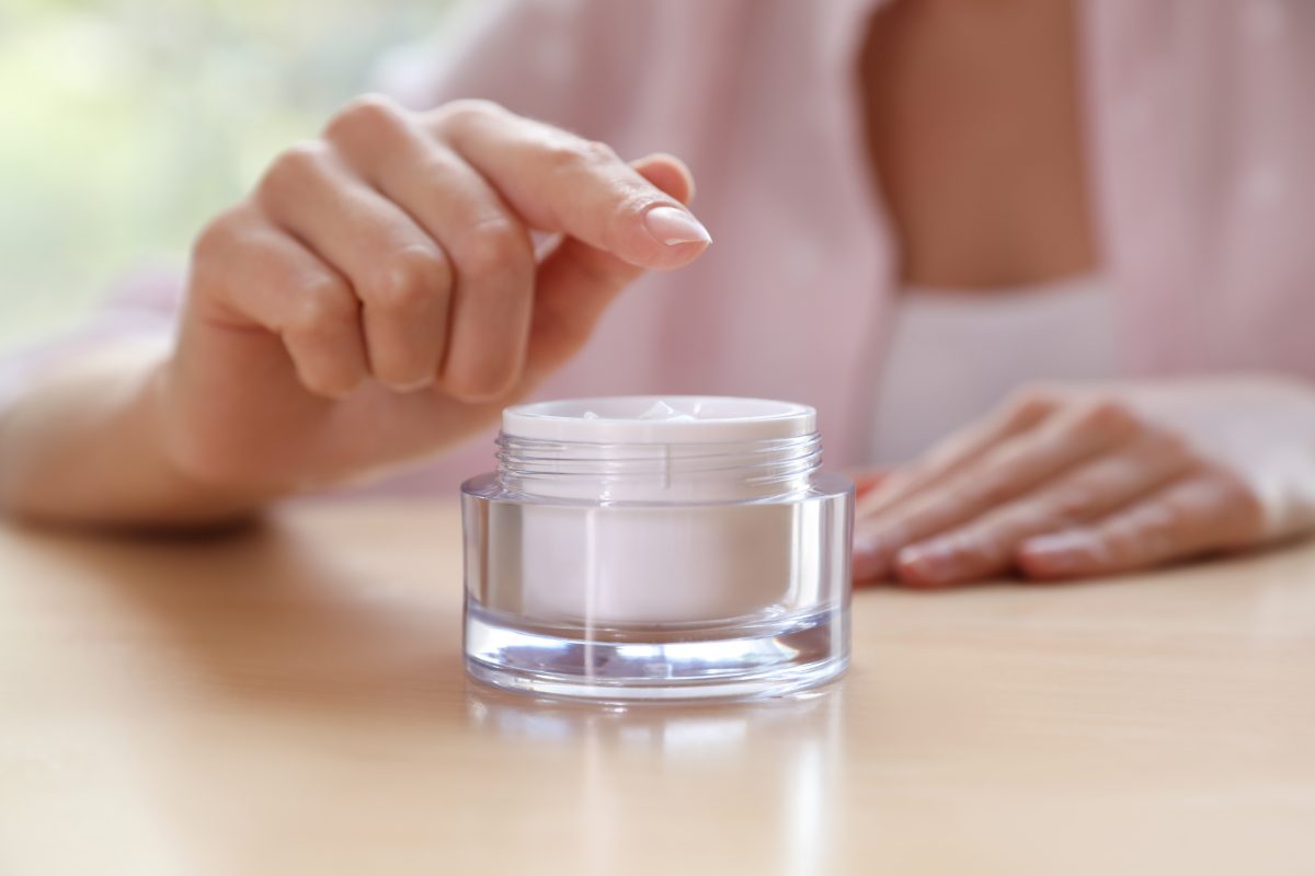 Woman with jar of moisturizing cream at table, closeup. Space for text. Gel vs. Dip Powder