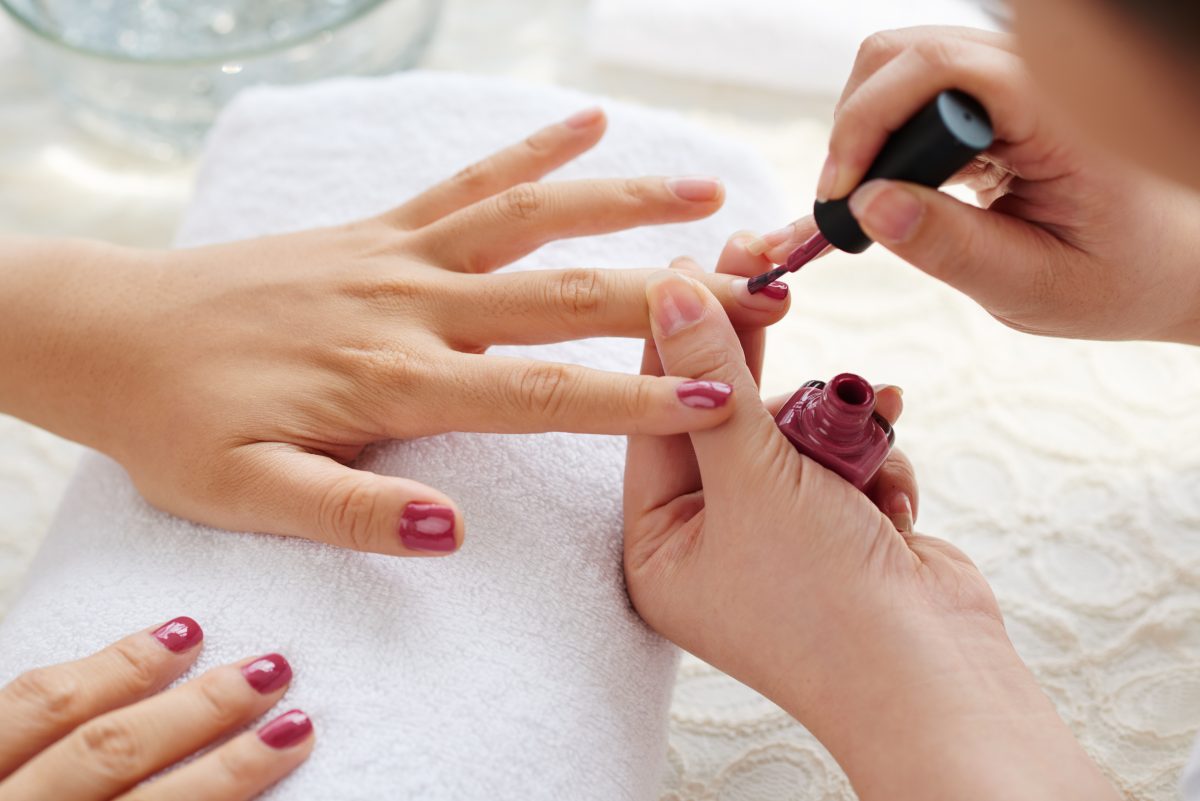 Master applying polish on fingernails on woman