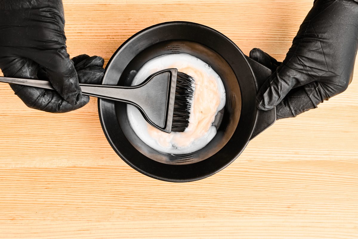Tools for hair dyeing in hairdresser hands on the wooden background. Coloring of hair at home. Professional Hair Color