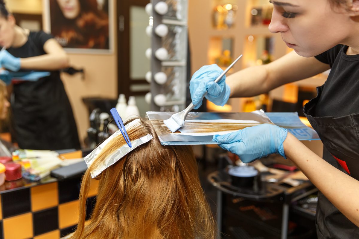 Professional hairdresser dyeing hair of her client.