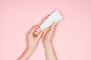 cropped view of female hands with hand cream isolated on pink