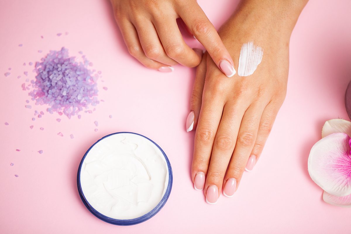 Woman applying hand cream at home, closeup.